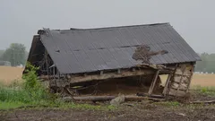 Stará drevená stodola na farme v zrútenom stave so známkami poškodenia