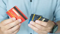 Muž drží viacero kreditných kariet v rukách, finančné produkty, výber platobnej karty
