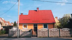 Dom s oranžovou stenou a červenou strechou na modrej oblohe