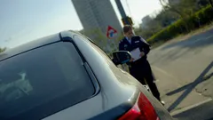 Policajt kontroluje auto na ceste v meste počas slnečného dňa.
